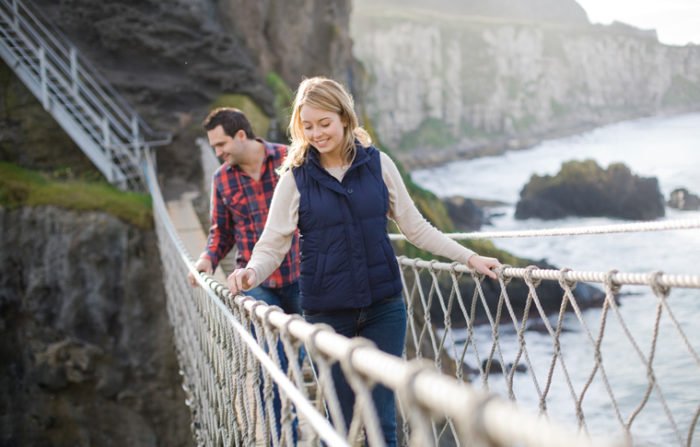 Crossing the Carrick-A-Rede rope bridge on a day tour Couple look over edge while crossing carrick-a-rede rope bridge
